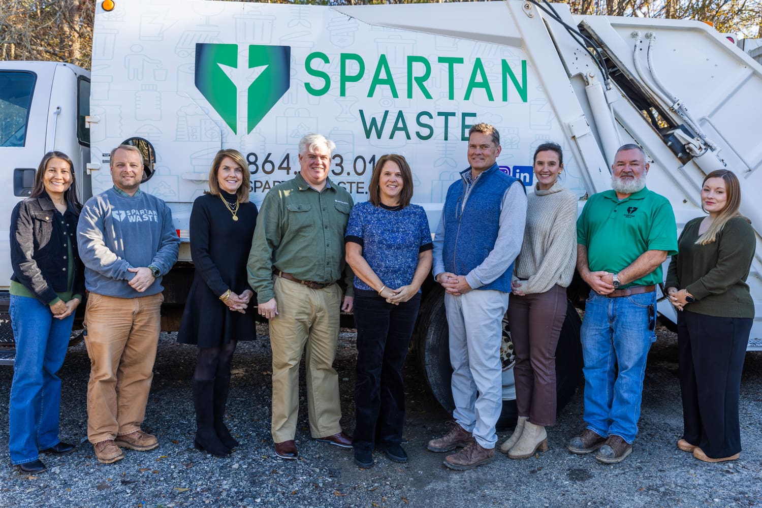 Spartan Waste team poses in front of a trash collection truck.